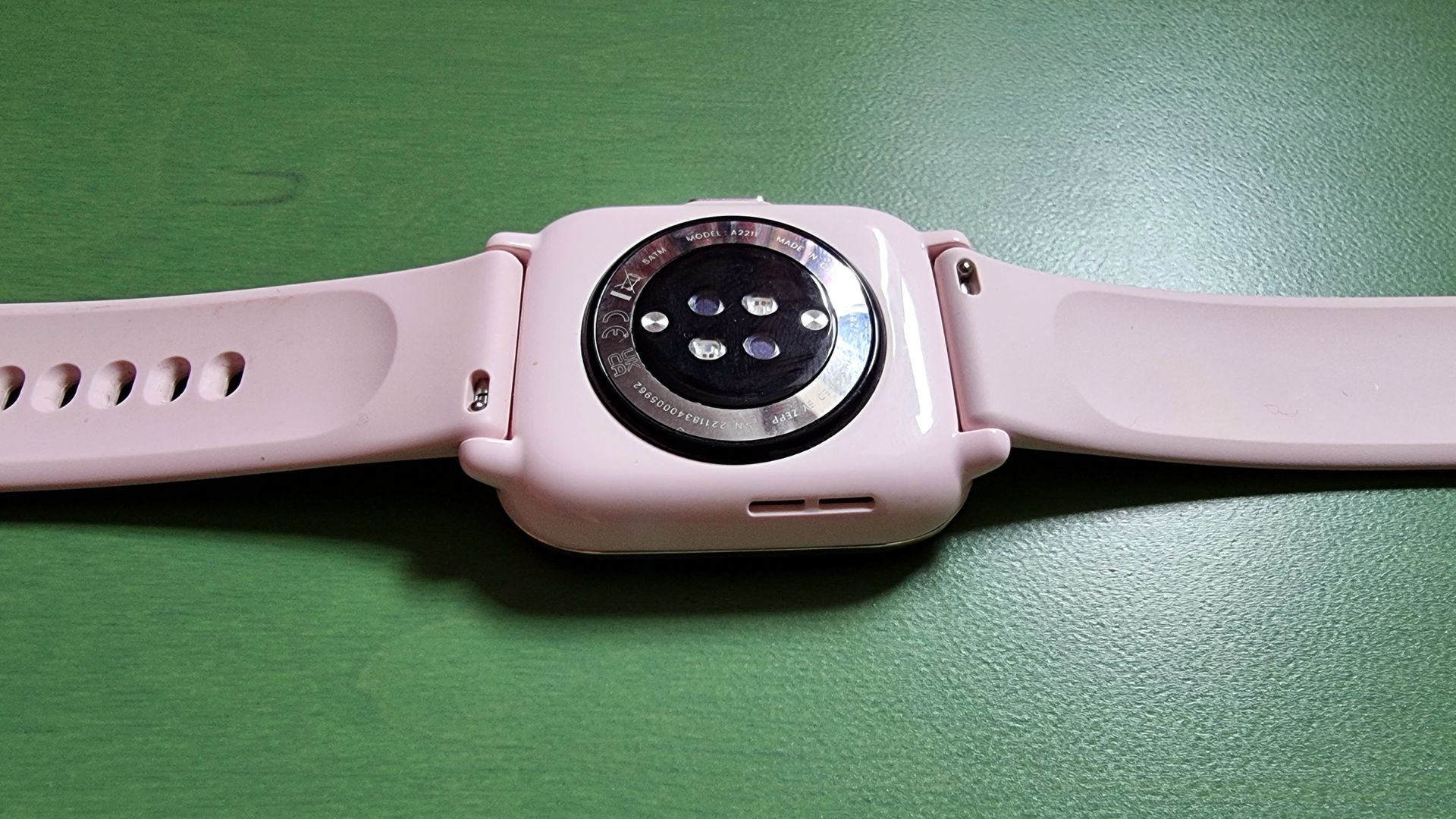 Back view of the Amazfit Active showing the sensors, on a green background.